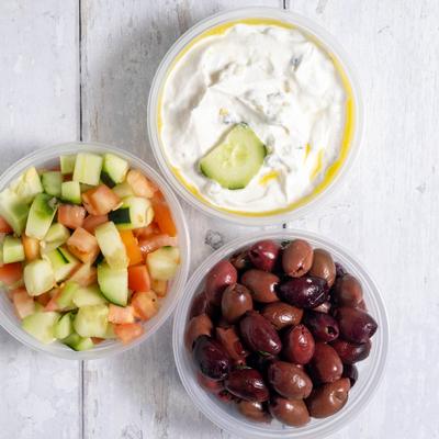 Side bowls with tzatziki sauce, chopped cucumber and tomato salad, and kalamata olives.