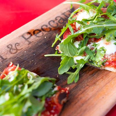 Two slices of pizza with arugula, mozzarella, and tomato sauce on a wooden board.