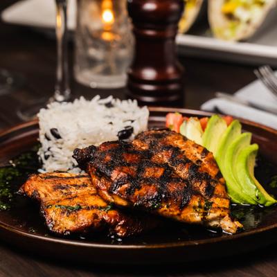 Grilled Chicken served with rice, avocado slices and diced tomato.