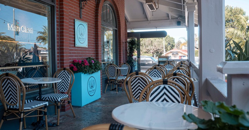 Outdoor seating area - black-white chevron chairs, white tables, a red brick building "Mon Chéri".