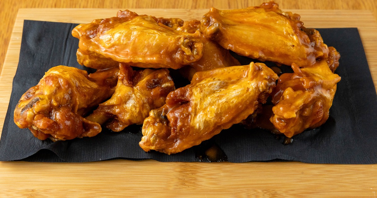 Mild Jumbo Cut Wings served on a wooden board over a black napkin