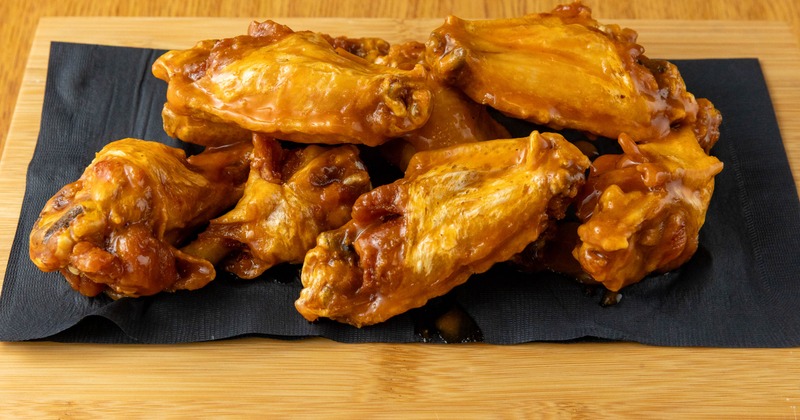 Mild Jumbo Cut Wings served on a wooden board over a black napkin