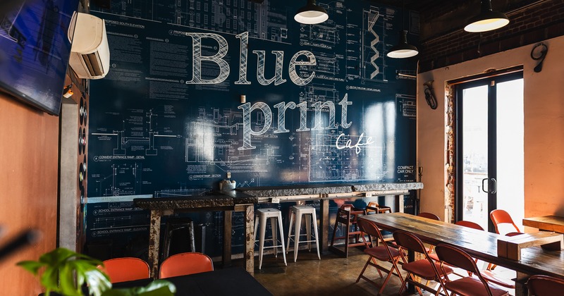 Modern and cozy interior seating area with a large mural with the sign “Blueprint Cafe” on the wall