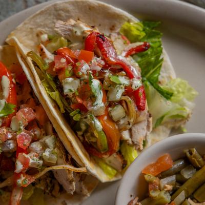 Soft tacos filled with chicken, peppers, and lettuce.