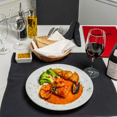Grouper fish with shrimp, clams, mussels, red sauce, veggies, and potatoes.
