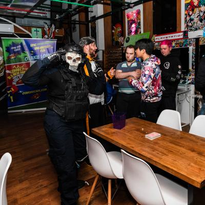 Five people  gathered around wooden table inside the gaming lounge.