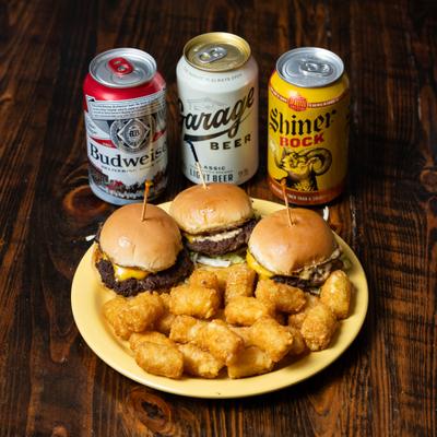 Sliders served with tater tots, alongside three cans of beer.