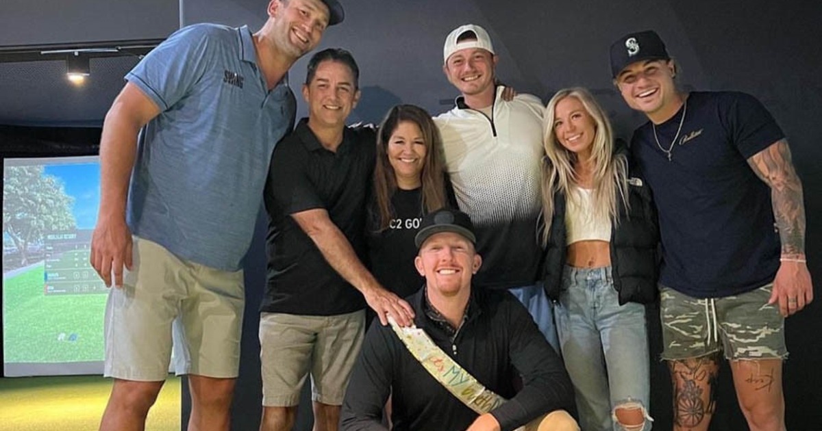 A group of people posing together in front of a golf simulator enclosure