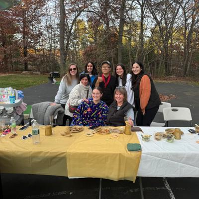 Group of people around a table with food at an outdoor gathering.