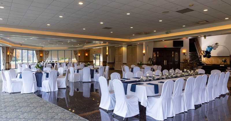 Interior, wedding venue, decorated white cloth tables with chairs, ready for guests