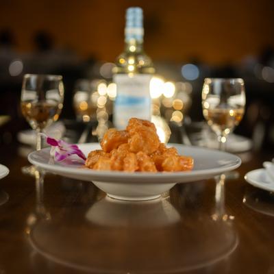 Rock shrimp served on a white plate with white wine glasses in the background.