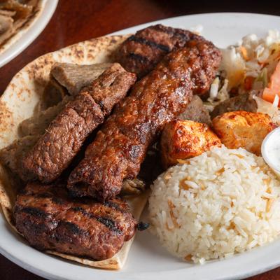 Mixed grill platter with rice, pita, and sauce.