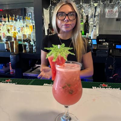A staff member and a served watermelon mojito.