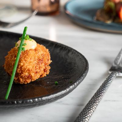 Prosciutto Croquettes topped with a creamy spicy sesame mayo and chives