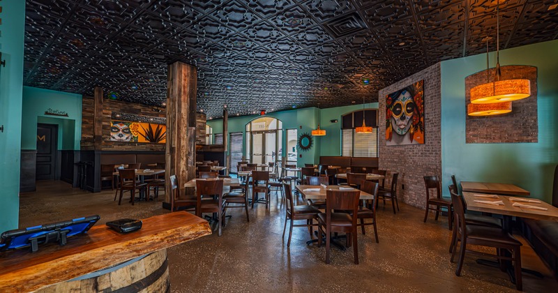 Cozy restaurant interior with teal walls, dark ornate ceiling, and wooden furniture