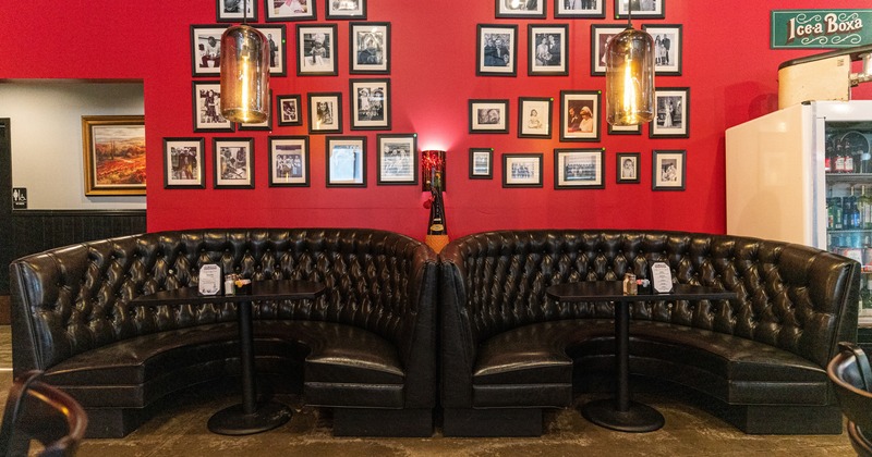 Interior, half circle booths by a wall decorated with framed retro photos