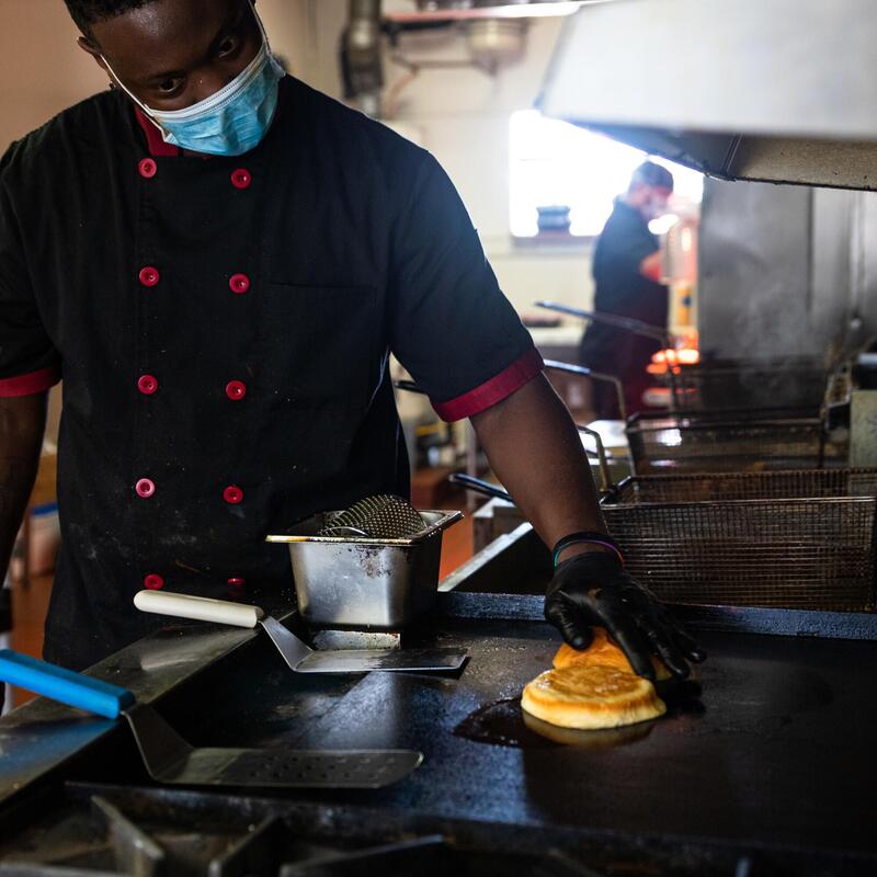 Chef with a sanitary mask grilling a bun