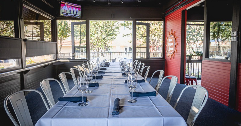 Interior, long table covered with white table cloth, with wine glasses and napkins