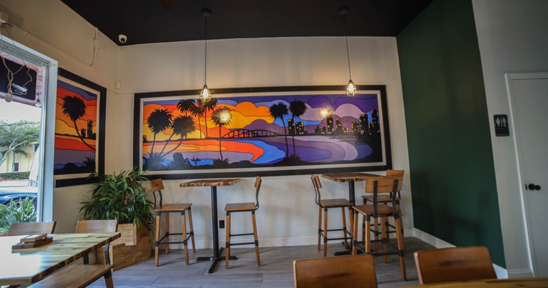 Interior, high tables and chairs near wall with picture