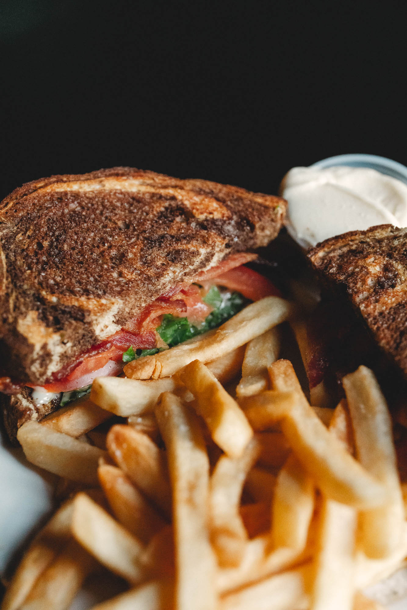 BLT sandwich with fries and dipping sauce, close up