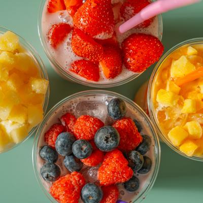 Colorful fruit smoothies topped with fresh berries and diced mango.