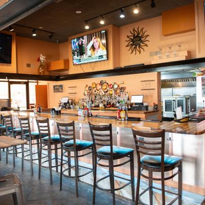 Bar featuring a long counter with high stools and televisions mounted on the wall.