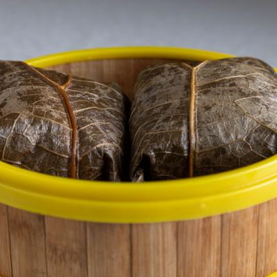 Sticky Rice in Lotus Leaf served in a yellow-rimmed bamboo steamer basket.