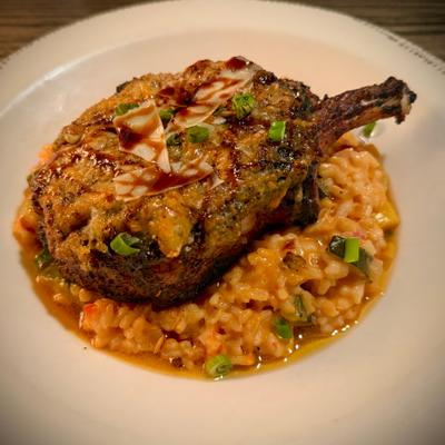 Grilled pork chop topped with barbecue sauce, served over creamy risotto.