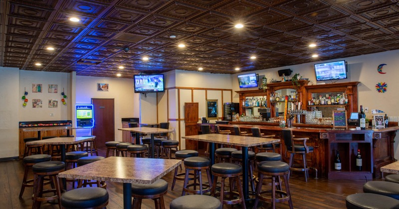 Interior, bar area and dining tables with bar stools, wall TVs