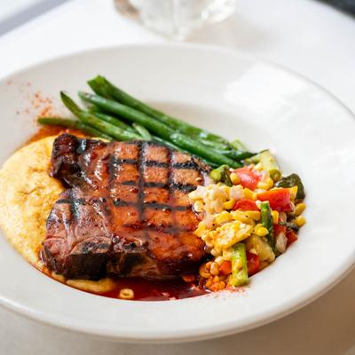 Bourbon Glazed Smoked Pork Chop, with cheddar grits, grilled vegetables, and sweet corn succotash