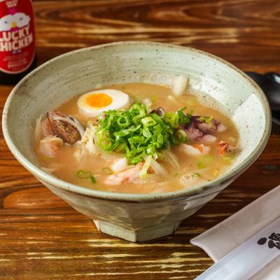 A bowl of seafood ramen topped with green onions and an egg.