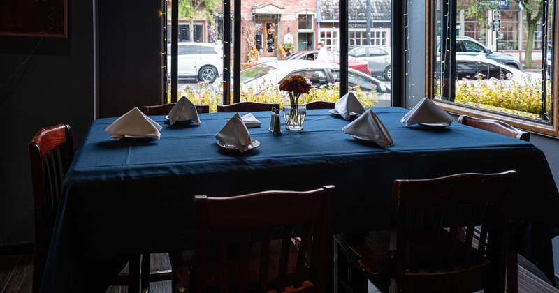 A dining table with a dark blue cloth and white napkins set in a restaurant