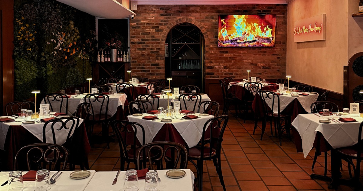 Restaurant dining room with set tables and a brick wall fireplace display