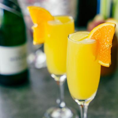 Yellow Mimosa cocktails, garnished with orange wedge.