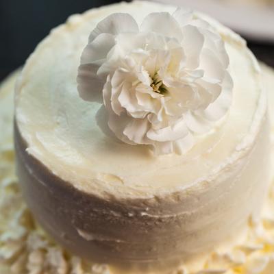 A white wedding cake decorated with a white flower on top.
