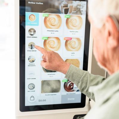 A customer using a self ordering coffee kiosk.