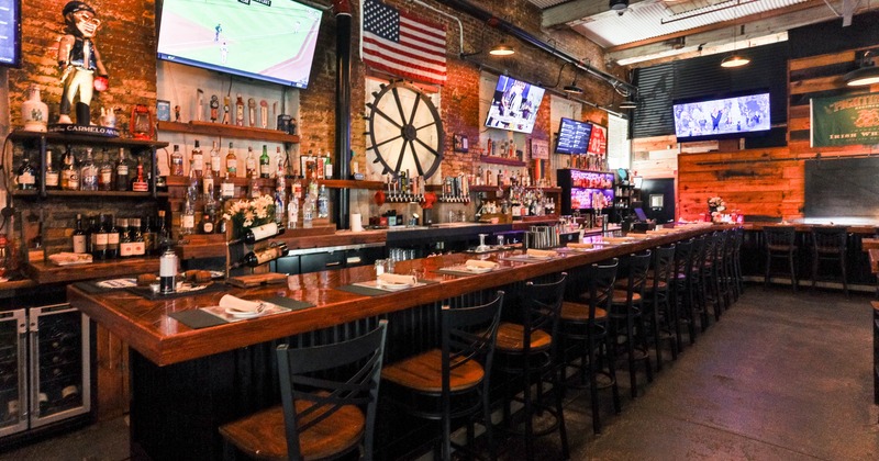 Interior, bar area, wooden counter top bar with stools, brick walls, concrete flooring