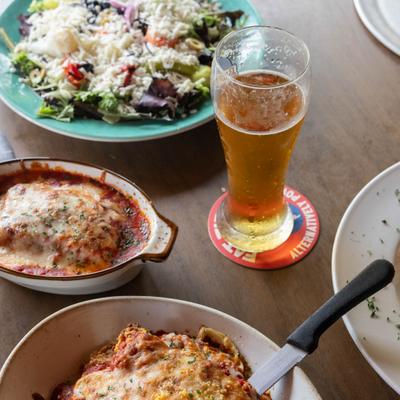 Glass of beer served on the table alongside variety of dishes.
