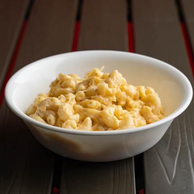 Bowl of creamy mac and cheese served in a wooden table.