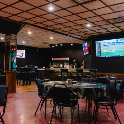 Spacious seating area with round tables and black chairs.