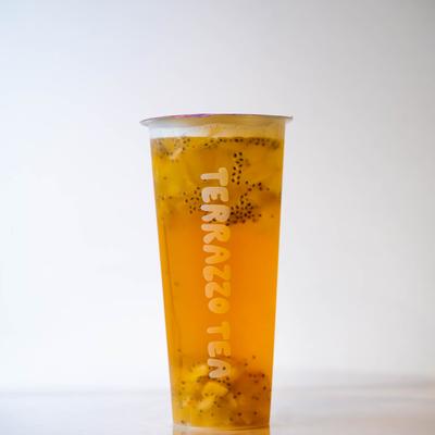 A tall, clear cup with vibrant orange tea and black seeds.