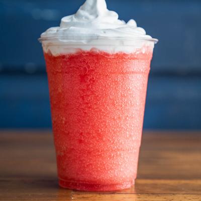 A red cocktail topped with whipped cream.