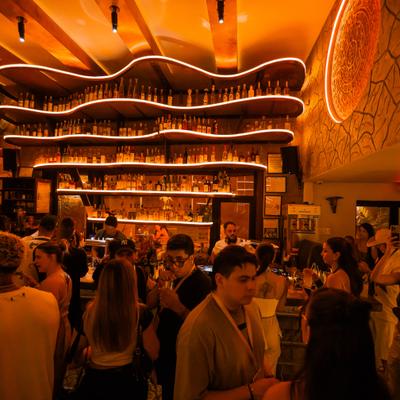 A vibrant bar scene with warm, ambient lighting, people enjoying drinks and socializing