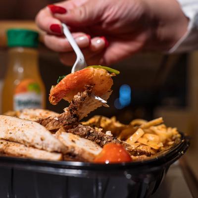 A hand holding a fork with a food bite.