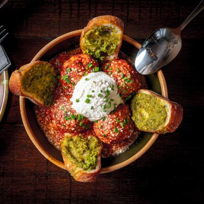 Meatballs topped with cheese beside herb toasted bread.