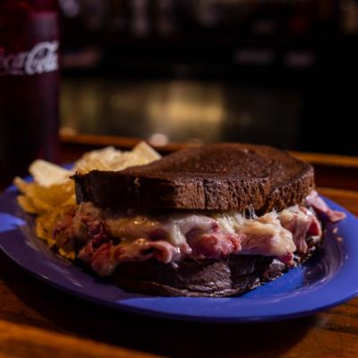 Reuben sandwich served on toasted rye bread with a side of chips.