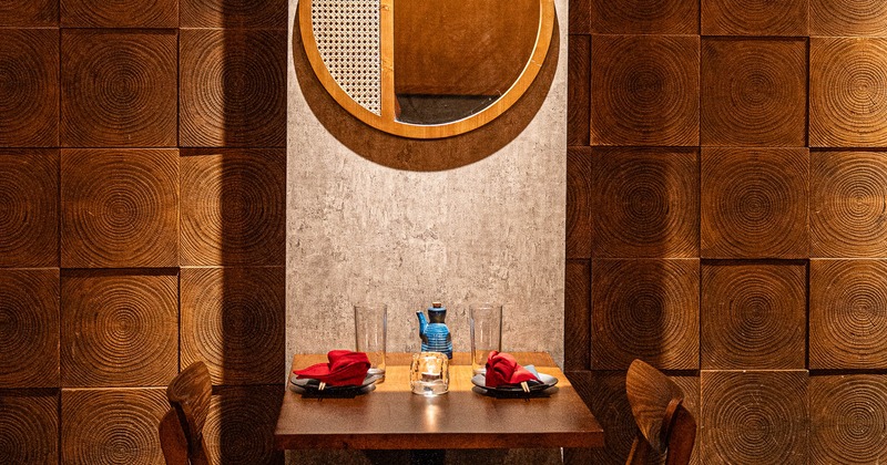 A small dining table set for two against a textured wooden background