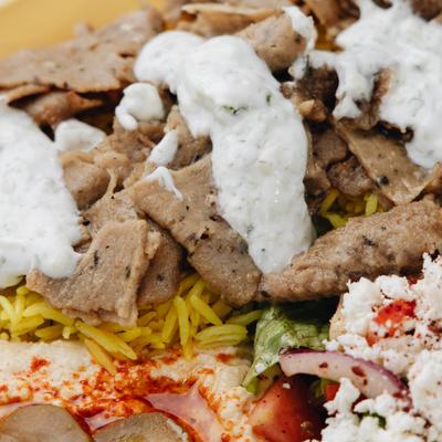 Gyro Plate featuring sliced meat topped with tzatziki sauce, close-up.