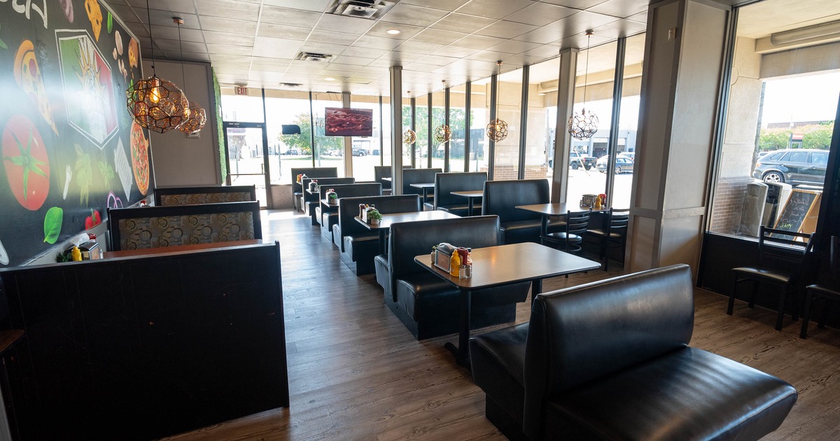 Interior of a modern restaurant with booths, a mural wall, and large windows