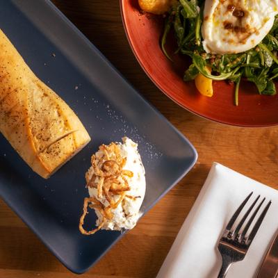 Bread and butter plate accompanied by a plate of Peach Burrata Salad, overhead view.